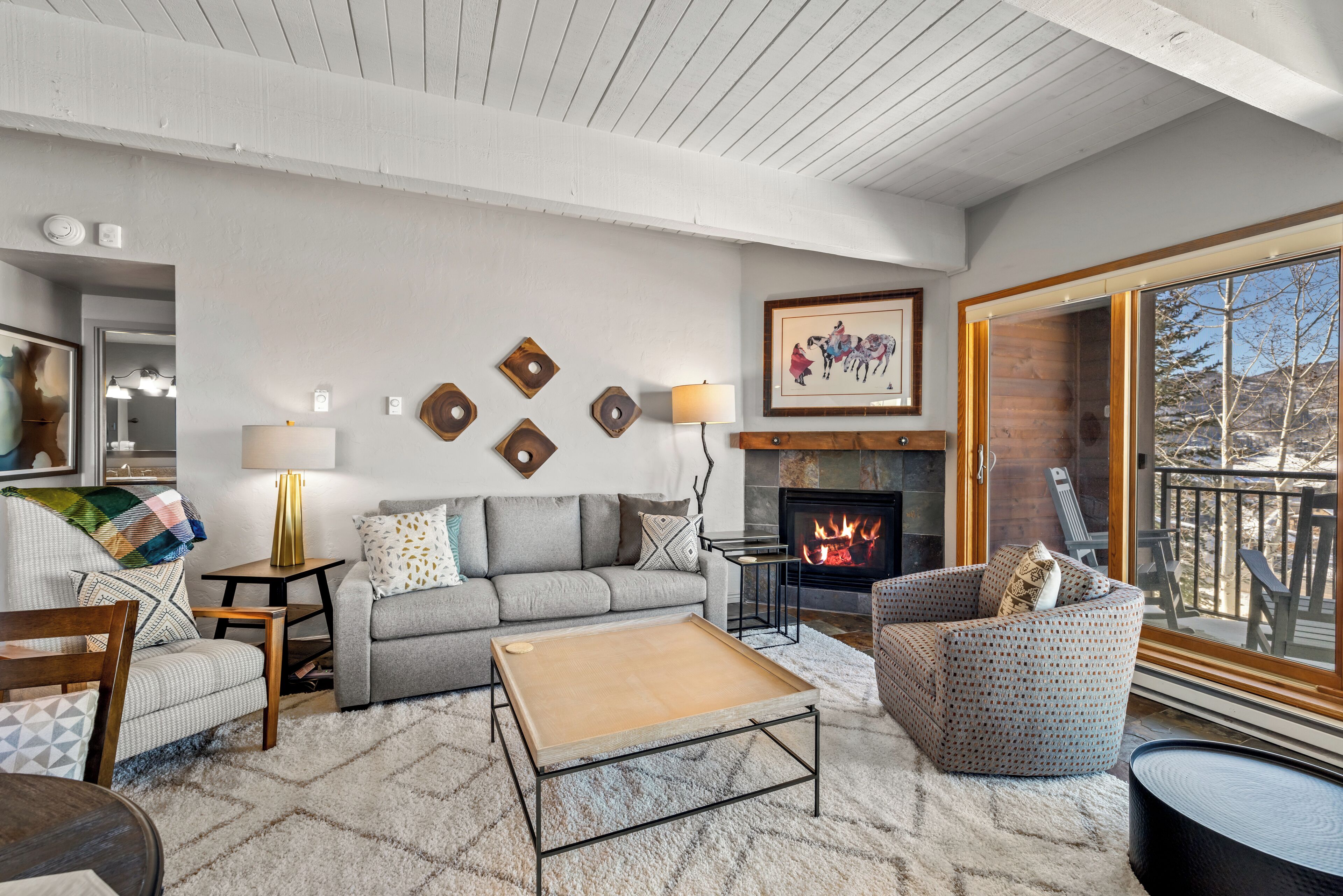 A cozy living room with a fireplace, a sofa, a coffee table, and a patterned armchair.
