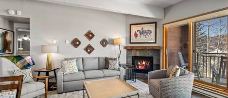 A cozy living room with a fireplace, a sofa, a coffee table, and a patterned armchair.
