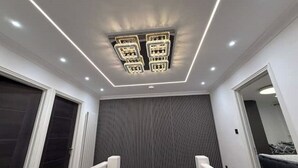 A modern interior with a ceiling light fixture, a dark vertical panel wall, and a staircase with white railings. - Peace house suite

 (Waterlooville)