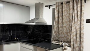 A kitchen with black marble backsplash, white cabinets, and a stainless steel range hood. - Peace house suite

 (Waterlooville)