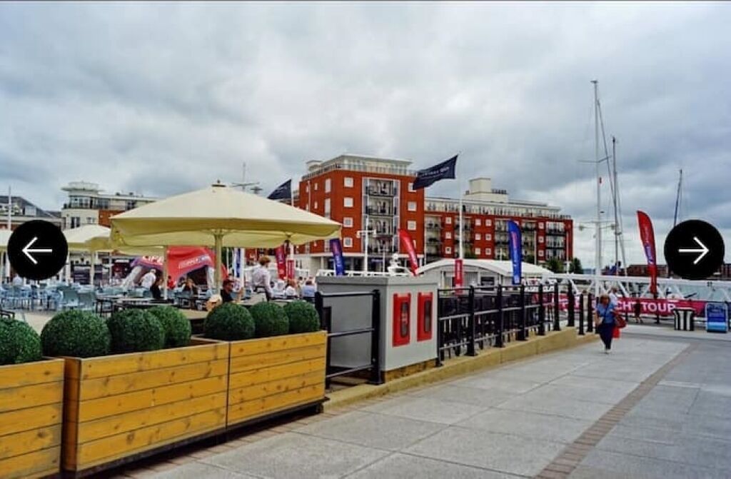 Een waterkantpromenade met terrasjes, een gebouw van rode baksteen en vlaggen.