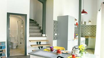 A modern kitchen with a dining area, wooden beams, and a staircase.