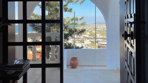 Una stanza con un'ampia porta finestra che dà su un balcone esterno con vista sulla città e sugli alberi.