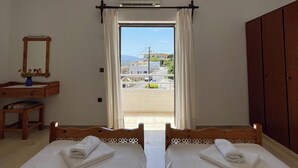 Una camera d'albergo con due letti, una scrivania con una sedia, uno specchio e un armadio.