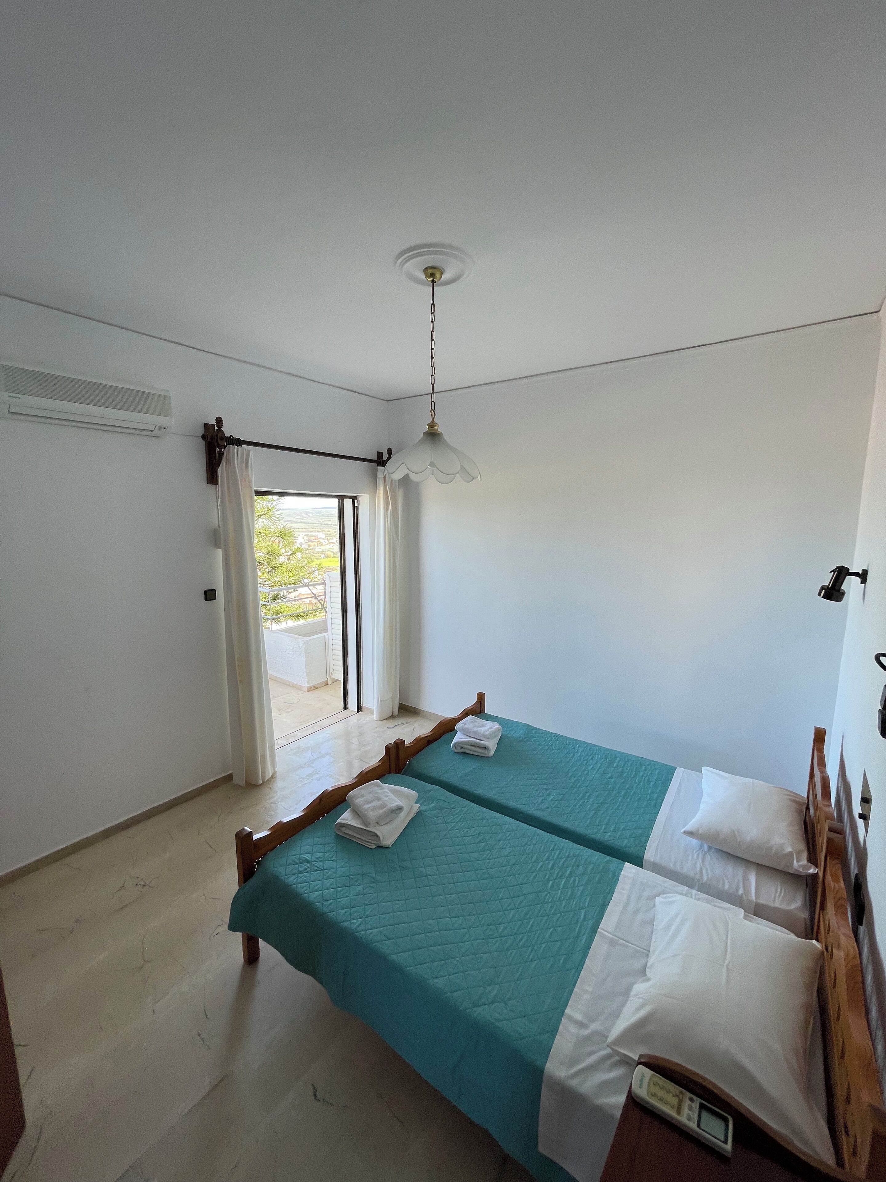 A bedroom with two beds, a ceiling fan, and a window with curtains.