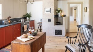 A kitchen with a wooden table, a red cabinet, and a brick fireplace.