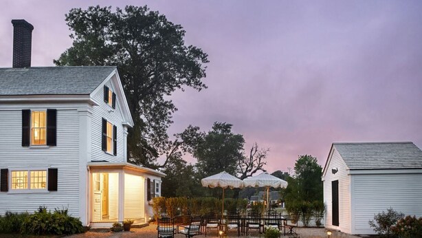 A two-story white house with a covered patio area featuring outdoor seating.