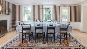 A dining room with a striped wallpaper, a fireplace, and a large window.