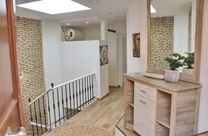 A modern interior with a staircase, a wooden vanity with a mirror, and a brick wall.