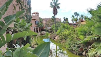 A courtyard with a water feature, palm trees, and buildings with arched windows.