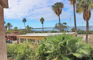 A coastal view with palm trees, a building with a flat roof, and a clear sky. - Apartamento Dúplex Bahia Sur (SAN FERNANDO)