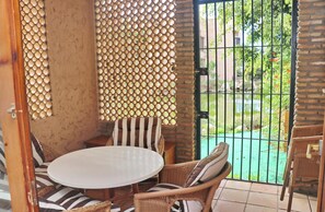 Relax in a serene garden setting with a seating area featuring a round table and wicker chairs.
