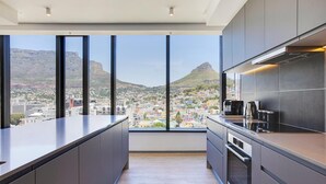 Una cocina moderna con ventanas amplias que ofrecen vistas a la ciudad y una montaña al fondo.