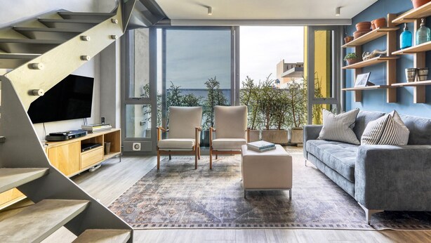 Un salon moderne avec un escalier, un canapé, une table basse et un téléviseur.