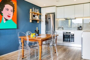 Eine moderne Küche mit einem Holzespeisetisch, klaren Stühlen, einem Edelstahlkühlschrank und einem Geschirrspüler.