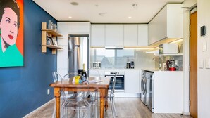 Une cuisine moderne avec un coin repas, des appareils en acier inoxydable et une vue sur l’extérieur.