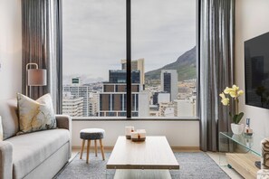 Una sala de estar moderna con un ventanal grande, un sofá, una mesita de centro y una mesita auxiliar con una planta.