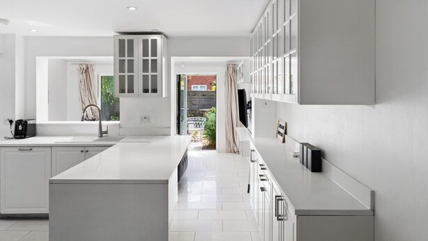 Una cocina moderna con armarios blancos, una isla central y vistas al patio trasero.