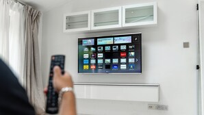 Una sala de estar moderna con un televisor montado que muestra diversas aplicaciones de transmisión.