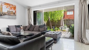 Una sala de estar moderna con un sofá modular, una mesa de centro de vidrio y vistas a un jardín a través de amplios ventanales.