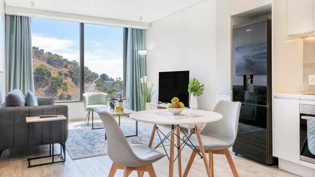 Un salon moderne comprenant un canapé, des fauteuils, une table à manger et un téléviseur.