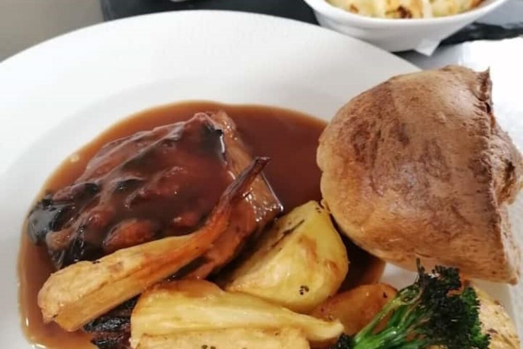 Un piatto con arrosto di manzo, pudding dello Yorkshire, patate arrosto e contorno di verdure.