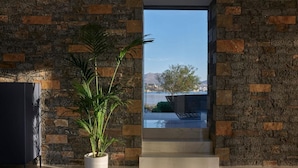 Ein modernes Interieur mit Steinwand, Topfpflanze und Blick auf ein Gewässer und Landschaft.