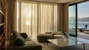 Ein modernes Wohnzimmer mit einer Couch, Hocker, einem Glastisch und einem Bücherregal.