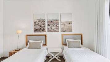 Une chambre d’hôtel avec deux lits, une petite table et une lampe.