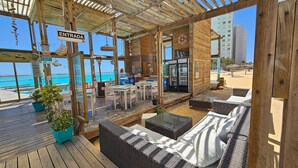 A wooden deck with outdoor seating, a sign reading 'ENTRADA,' and a view of the ocean. - Oceana Suites Laguna del Mar (La Serena)