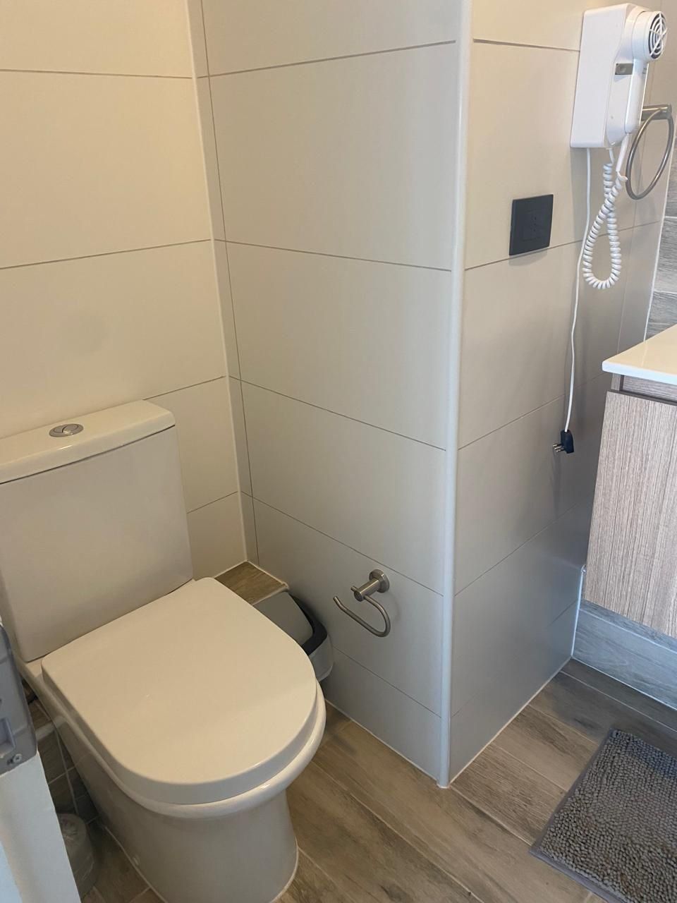 A bathroom with a toilet, a shower area, and a hand dryer.