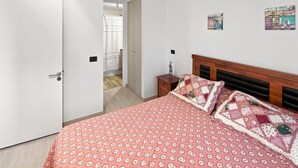 Ein Schlafzimmer mit einem Bett, einem Nachttisch, einer Tür und einer Wand mit einem Poster.