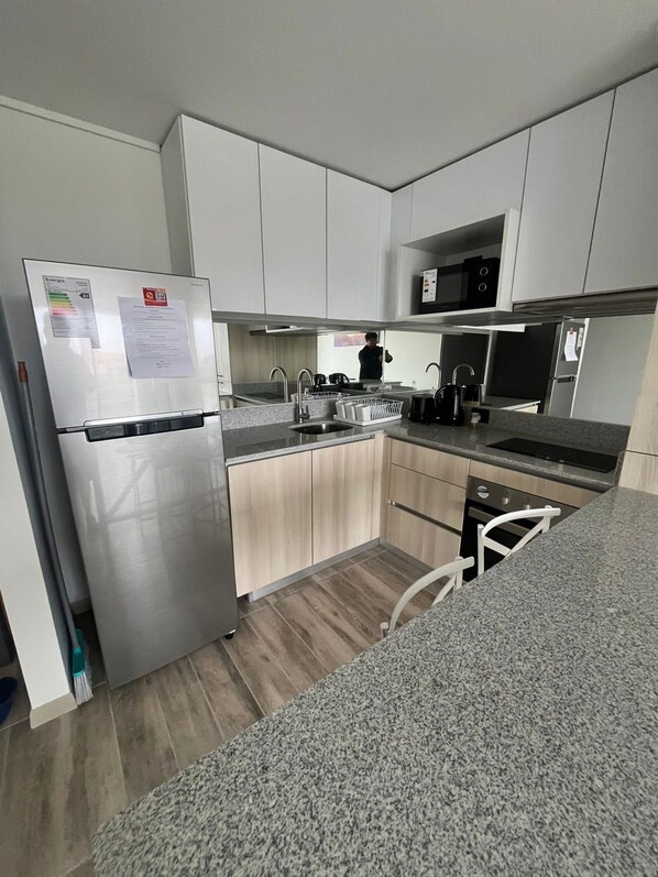 A modern kitchen with stainless steel appliances, wooden cabinets, and a granite countertop.