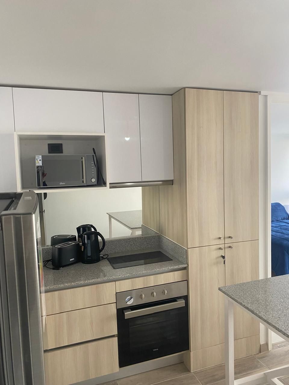 Cozinha compacta equipada com micro-ondas, torradeira, cafeteira e forno.