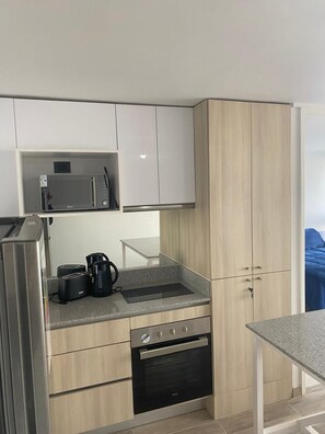 Een functionele keuken met een magnetron, broodrooster, koffiezetapparaat en oven.