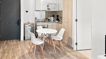 A compact kitchen with white cabinets, a built-in oven, and a dining area with a round table and four chairs.