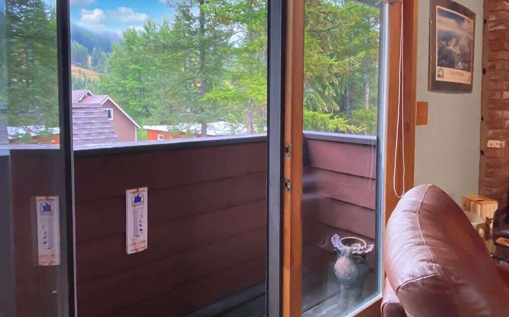 A room with a sliding glass door leading to a balcony, a brown leather chair, and a small table with a vase.