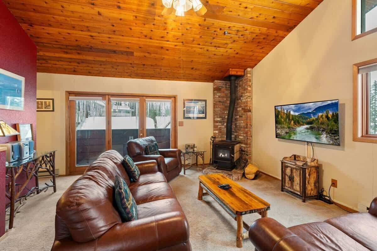 A cozy living room with a leather sofa, a wooden coffee table, a fireplace, and a television.