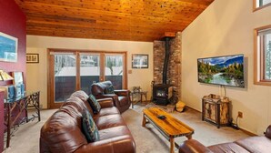 A cozy living room with a leather sofa, a wooden coffee table, a fireplace, and a television.