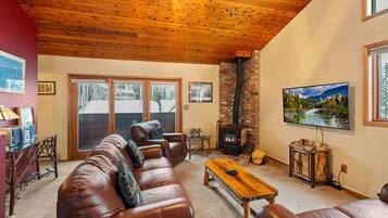 A cozy living room with a leather sofa, a wooden coffee table, a fireplace, and a television.