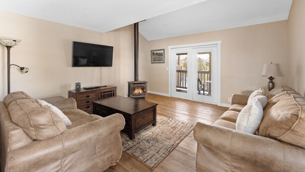 A living room with a fireplace, leather sofas, a flat-screen TV, and a large window. - Townhome w/ Private Sauna that's Close to Breck's Main Street & Bus Route! (Breckenridge)