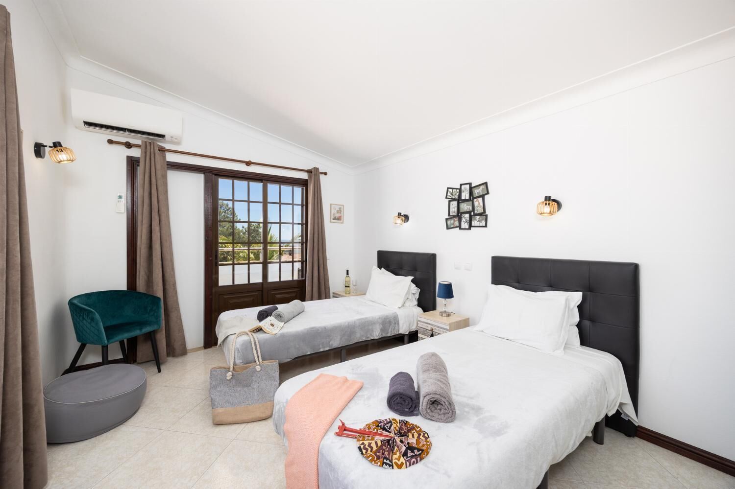 Une chambre d’hôtel avec deux lits, une chaise, une petite table et une fenêtre avec des rideaux.