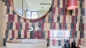A bathroom with a large white basin, a round mirror, a modern faucet, and a colorful brick-patterned wall. - Hedera Estate, Villa Hedera XX (Dubrovnik)
