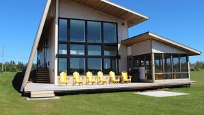 A modern building with large windows, a sloped roof, and outdoor seating. - 5-bedroom Waterfront Home In Brackley, Minutes To National Park Beaches (York)