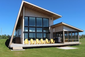 A modern building with large windows, a sloped roof, and outdoor seating.