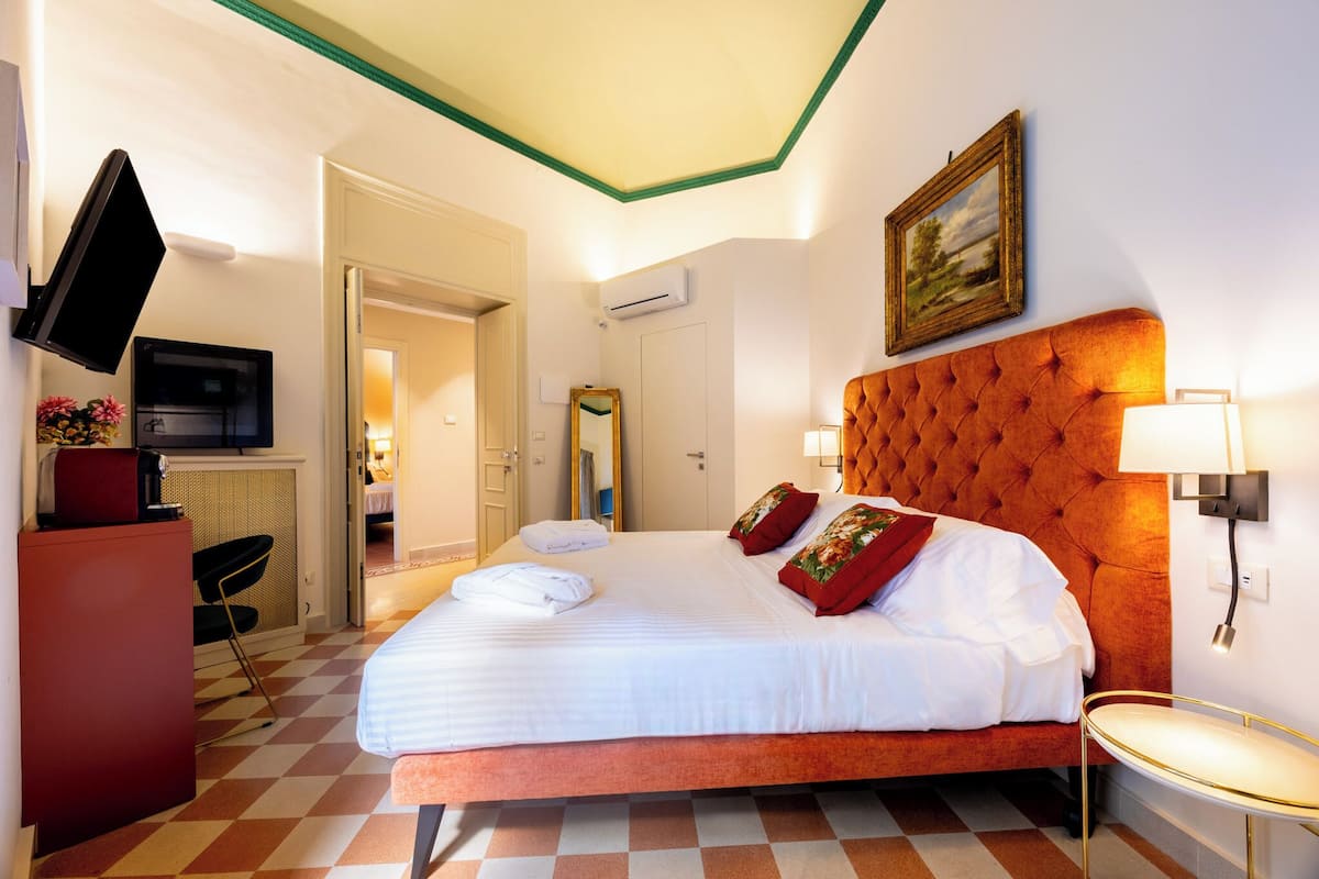 A hotel room with a large bed, a television, a desk, and a mirror.