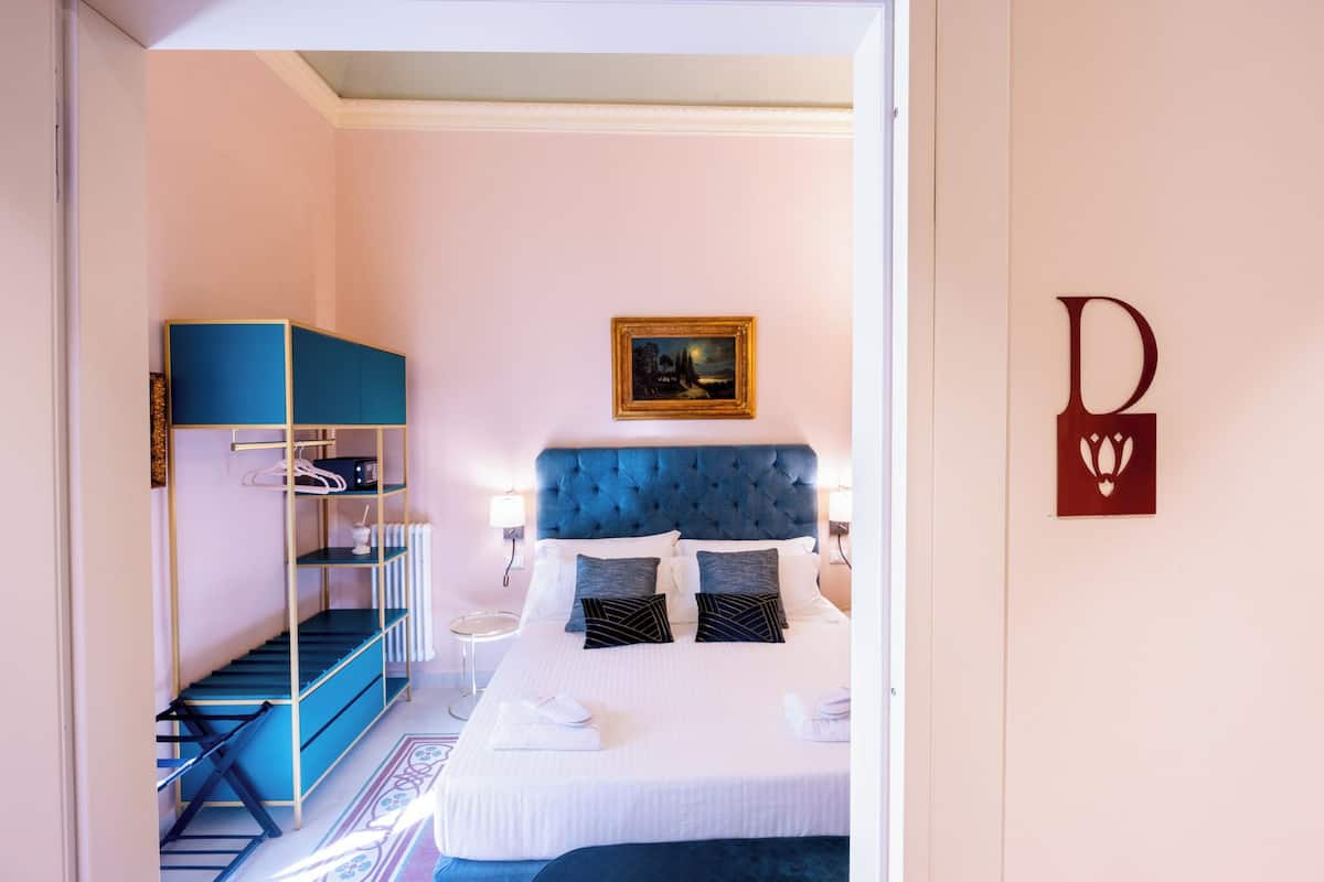 A bedroom with a bed, a blue headboard, a framed picture, and a blue shelving unit.