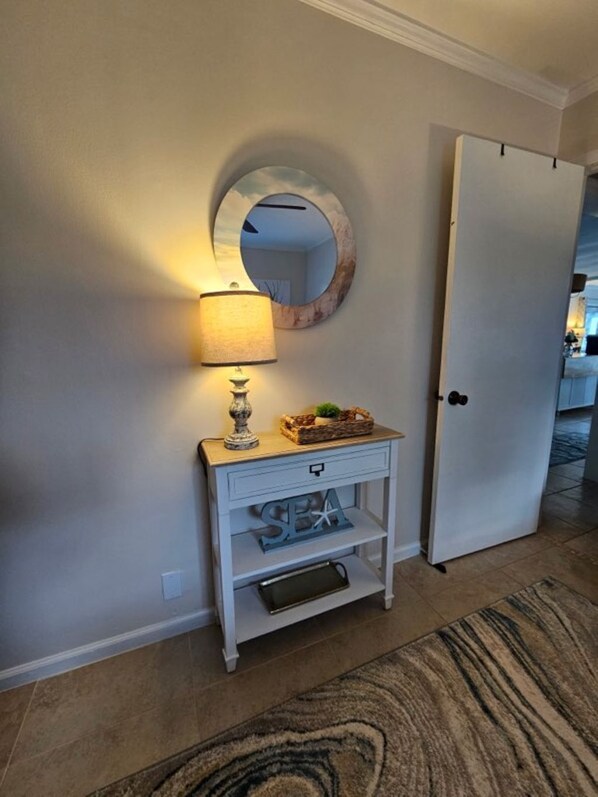 A hallway with a white console table, a lamp, a mirror, and a door. - Stunning Bay View from Living Area, Dockage, Oversized Lot, 2nd Story Tiki Hut (Tavernier)