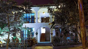 A two-story building with a staircase leading to the entrance, surrounded by tropical plants. - Tuna Nungwi Beach Bungalow (Nungwi)
