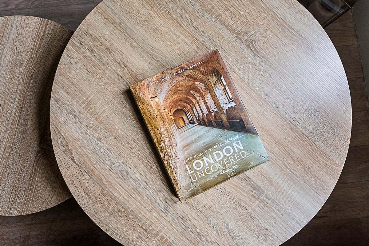 En bok med titeln ”LONDON UNCOVERED” ligger på ett runt träbord.